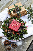 Weihnachtliches Gesteck mit roter Kerze und Tannenzapfen auf Holztisch