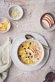 Porridge mit Apfelscheiben, Orange, Granatapfelkernen und Mandeln