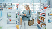 Woman choosing medicine in pharmacy