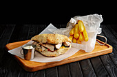 Pita sandwich filled with meat and vegetables with a side of chips