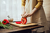 Man slices fresh peppers on a wooden board