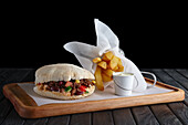 Pita sandwich with minced meat, beans and vegetables, served with chips and dip