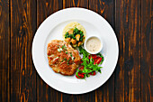 Pork chop with mashed potatoes, tomatoes and rocket salad