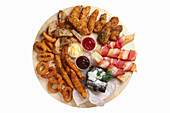 Finger food platter with onion rings, chicken wings, puff pastry sticks with bacon and dips