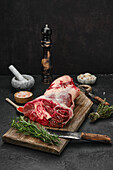 Raw beef shank on a wooden board with rosemary