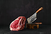 Raw rib-eye steak on the bone with cleaver