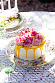 Torte mit Spritzdekor und gelbem Guss auf floralem Porzellanteller