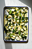 Roughly sliced courgette with olive oil and oregano before roasting