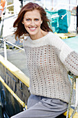 Rothaarige Frau in braun-beigem Strickpullover mit Lochmuster