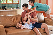 Father playing with children on sofa