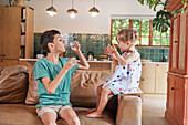 Brother and sister blowing bubbles at home