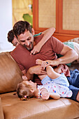 Father playing with children on sofa