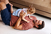 Father playing with daughter at home