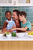 Father embracing children in kitchen