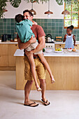 Happy father carrying son in kitchen