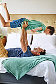 Father and son playing on bed