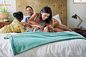 Parents with daughters relaxing on bed