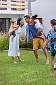 Parents with children playing in backyard