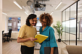 Smiling workers looking at file in creative studio