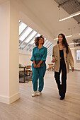 Two smiling women walking in modern studio