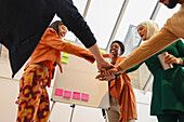 Employees celebrating during team meeting in office