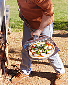 Margherita pizza is placed in the wood-fired oven