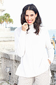 Long-haired young woman in white turtleneck jumper, laughing, red lipstick