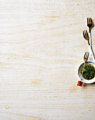 Fine herb pesto with forks on a light brown wooden table