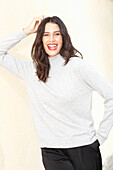 Long-haired young woman in white turtleneck jumper, laughing, red lipstick