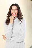 Long-haired young woman in white turtleneck jumper, laughing, red lipstick