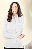 Long-haired young woman in white turtleneck jumper, laughing, red lipstick