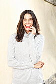 Long-haired young woman in white turtleneck jumper, laughing, red lipstick