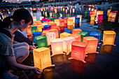 Woman float lanterns on the river, in front of Atomic Bomb Dome with floating lamps on Motoyasu-gawa River during Peace Memorial Ceremony every August 6 in Hiroshima, Japan