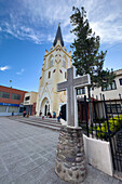 A metal cross in front of the St. Peter the Apostle Church in San Pedro de Jujuy, Argentina, with people also in front.