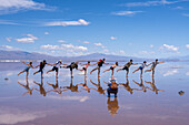 Tourists posing for a picture on the Salinas Grandes salt flats on the altiplano in Argentina. Recent rains left a shallow sheet of water on the flats.