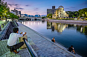 Tourists in Hiroshima Peace Memorial (Genbaku Dome, Atomic Bomb Dome or A-Bomb Dome) and Motoyasu River in Hiroshima, Japan