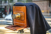 A close up of a classic wooden vintage camera with a brass lens, set outdoors in a scenic location in Sevilla, Spain.