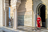 Rabat, Morocco, Apr 24 2015, A guard stands watch at the Mausoleum of Mohammed V, with a visitor walking past on the polished marble floor, as the sun sets.