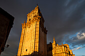 The Cathedral\'s towers glow warmly in the golden light of sunset over El Burgo de Osma, highlighting its historic architecture against a dramatic sky.