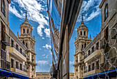 Tower of the stunning cathedral in Jaen reflected in a shop window, showcasing the architectural beauty of Andalucia, Spain under a vibrant blue sky.