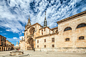 The majestic facade of the Cathedral in El Burgo de Osma showcases intricate architecture against a beautiful sky in Soria, Spain.