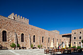 This historic castle-turned-hotel showcases stunning architecture against a clear blue sky, inviting guests to enjoy its charming courtyard.