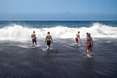 A group of bathers enjoying the waves at Bollullo Beach on the northern coast of Tenerife, La Orotava, Canary Islands, Spain. Long exposure.