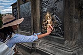 Tourists touching a plaque that is part of the statue St. John of Nepomuk for good luck, Prague.