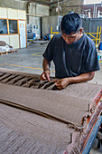 A worker ties the yarn by hand to make tassels at Hilandería Warmi, a weaving mill in Palpalá, Argentina.