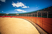 A panoramic view of an empty portable bullring in Aznalcazar, Sevilla, Spain, showcasing the traditional arena under a vivid blue sky.