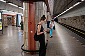 People using smartphone while waiting in Prague Metro platform