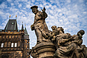 Statue des Heiligen Ivo von Kermartin und alter Turm an der Karlsbrücke in Prag