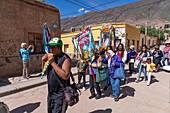 An indigenous man playing the siku panpipes leads a religious procession in front of the church in Tilcara, Argentina.