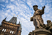 Statue des Heiligen Ivo von Kermartin und alter Turm an der Karlsbrücke in Prag